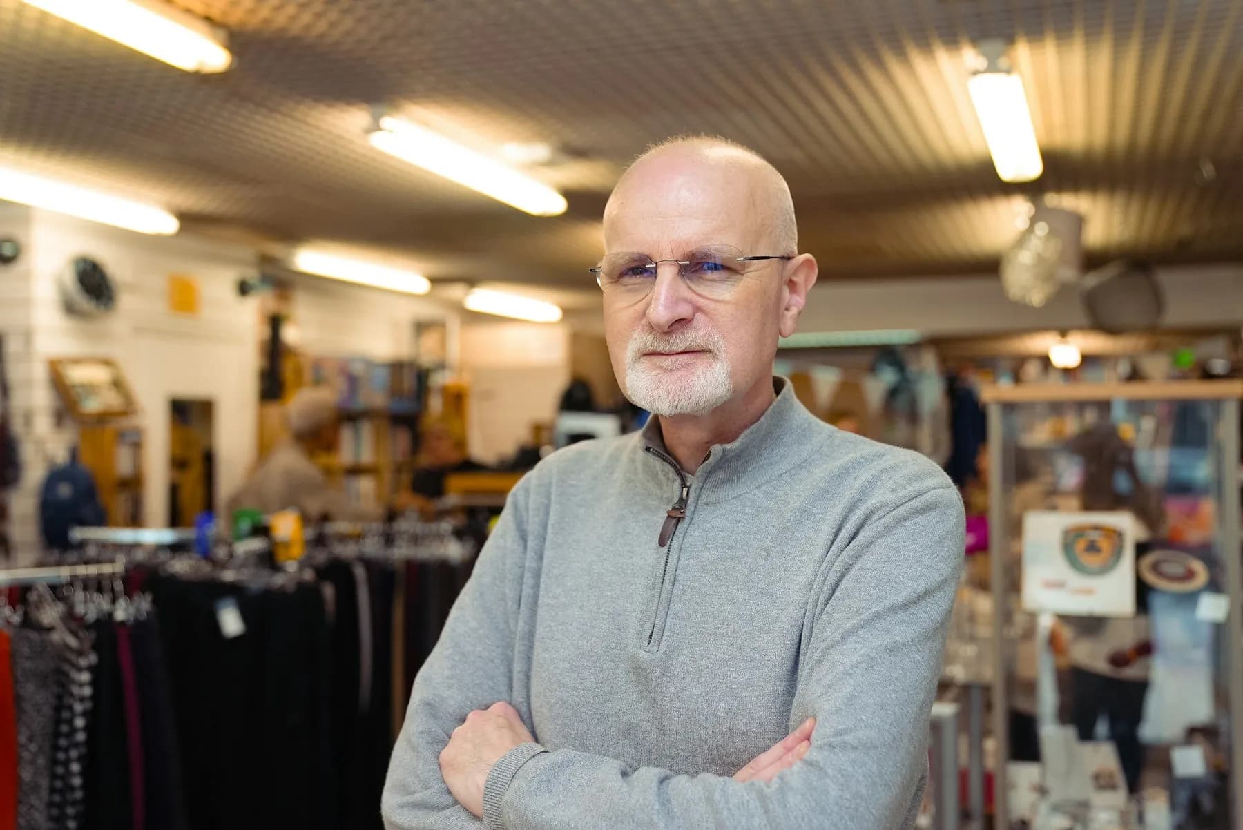 A shop owner with his arms folded in his clothing store
